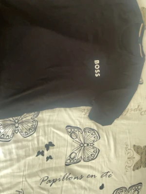 Svart t-shirt från BOSS - Snygg svart t-shirt från BOSS med klassisk rund hals och vit BOSS-logga tryckt på bröstet. Enkel och stilren design som passar till allt. Tillverkad i mjuk bomull för skön känsla hela dagen.