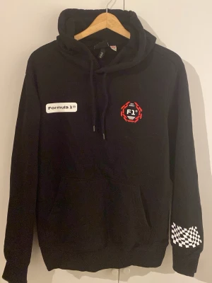 Formula 1 - En skön Formula 1 hoodie perfekt för om man ska va med vänner eller bara vara hemma. Skön på insidan och utsidan. Den är en regular fit, 175 bredd och 92 i armarna 