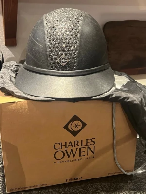 Charles Owen ridhjälm sp8 sparkly plus black leather look  - Säljer en riktigt snygg svart Charles Owen ridhjälm. Modellen är black leather look, black sparkle centre SP8 Plus. Köptes ny 2021, använts sparsamt på tävling samt enstaka träningstillfällen. Ramlat av 2 gånger, därav syns två små repor/sträck (kolla näst sista bild). Utöver detta är hjälmen i bra skick. Har förvarats i påsen och kartong, detta medföljer såklart vid köp. 