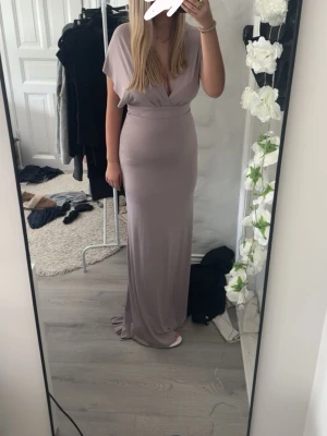Ljuslila långklänning med omlott - Köp gärna min balklänning som jag hade på 9ans bal, inga fläckar, ser precis ut som ny. Jag är ca 168 cm lång och den var lite lång utan klackar. Jag har vanligtvis storlek M men skulle säga att denna är närmare storlek S. Kan knytas på lassor av sätt och så finns det ett litet släp. Om den skulle vara för lång kan man bara klippa av den för det är sånt material som du inte behöver sy i.