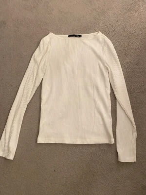 ribbad långärmad  - Säljer en enkel och vit långärmad topp. Toppen är ribbad och har en rak passform med rundad halsringning. 