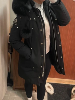 Svart dunjacka från Moose Knuckles - Jättefint skick! Så gott som ny, använd i en vinter ca 2-3 månader.  Storlek M men passar S.                          🩷Säljer en svart lång dunjacka från Moose Knuckles med pälskantad huva och snygga detaljer som silverfärgade knappar och dragkedja.🩷
