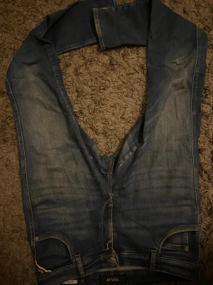 Blå jeans från Replay, storlek 31 - Säljer ett par klassiska blå jeans från Replay i modellen Katewin. Jeansen har raka ben, fem fickor och snygga slitningar framtill. De är tillverkade i jeansmaterial och har en normal passform. Perfekta för dig som gillar en tidlös look.