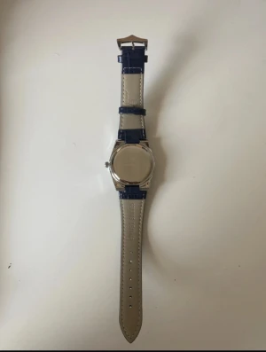 Poedagar kvartz 41mm läderband - Snygg klocka från Pedagar med mörkblå urtavla och matchande blått läderband med krokodilstruktur. Boetten är i silverfärgat stål och har en klassisk rund form. Urtavlan har dag- och datumvisning samt tydliga indexmarkeringar. Perfekt accessoar för dig som gillar stilrena detaljer.