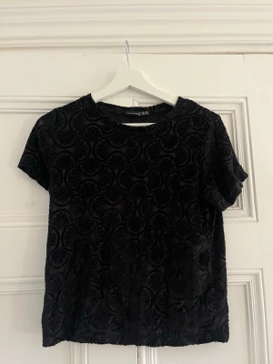Svart genomskinlig sammetstopp  - Säljer en svart topp från Atmosphere i mjuk sammet med korta ärmar. Toppen har ett coolt unikt mönster och älskar att den är lite genomskinlig. Tveka inte på att höra av dig om du har frågor❤️