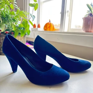 Mörkblå pumps från Graceland - Snygga mörkblå pumps från Graceland med rund tå och klack. Skorna är i mockaimitation och har en klassisk siluett som passar till många olika outfits. Sulan har ett blommigt mönster för extra grepp. Perfekta för dig som vill ha en stilren och elegant look.