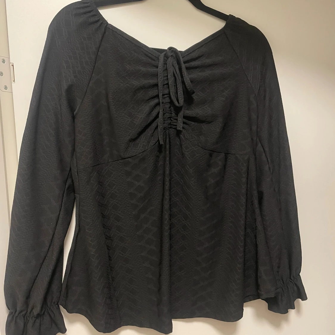 Svart blus med knyt och strukturmönster