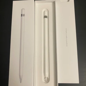 Apple Pencil (1st Generation) - Apple Pencil 1st Gen i originalförpackning. Perfekt för iPad, ger exakt och smidig skriv- och ritupplevelse. Pennan och tillbehör ser ut att vara i mycket gott skick, inga synliga repor eller skador. Komplett med laddadapter och extra spets.