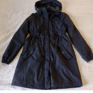 Svart fodrar kappa med huva - storlek 34/36 - Svart fodrad men lätt kappa. Storlek 34/36. Knappt använd och i fint skick (ett pyttelitet hål på midjebandet).