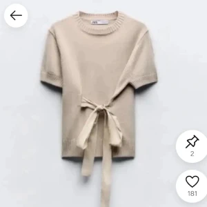 Beige stickad topp med knyt från Zara - Superfin beige stickad topp från Zara med korta ärmar och snygg knytning i midjan. Rund halsringning och ribbade detaljer vid ärmslut och nederkant. Perfekt för lager-på-lager och en chill men ändå trendig look. 