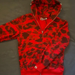 Bape Full-Zip Red Camo Hoodie - Använd ett fåtal gånger i mycket bra skick✅ Storlek: XL men passar som ca L 📏 Skickas inom 1 dag 📦 Full zip, och Embroidery på luva  Kontakta gärna för mer info ☺️