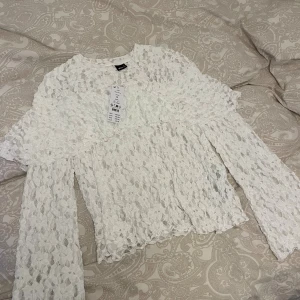 Vit spetsblus från Gina Tricot - Superfin vit spetsblus från Gina Tricot. Blusen har långa, vida ärmar. Ny