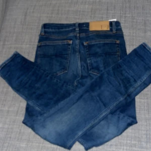 Tiger of Sweden Shelly jeans blå 28/30 - Snygga blå jeans från Tiger of Sweden i modellen Shelly. Klassisk femficksdesign med raka ben och normal passform. Jeansen har en mörkblå tvätt och är tillverkade i slitstarkt bomullsmaterial. Perfekta för dig som gillar stilrena och tidlösa jeans.