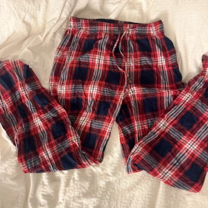 Rödrutiga mjukisbyxor från Gina Tricot - Rödrutiga mjukisbyxor från Gina Tricot i storlek XS. Byxorna har snörning i midjan och är gjorda i mjukt bomullstyg. Perfekta för chill dagar hemma med sin loose fit och klassiska rutiga mönster i rött, blått och vitt.