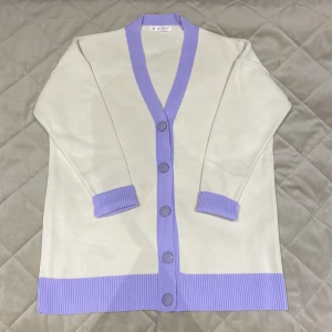cardigan/kofta med lila detaljer | Mixray - Superfin vit kofta/cardigan (Mixray) med breda ribbade lila kanter och stora matchande knappar. Långärmad och i mjukt stickat material, perfekt för kallare väder. Använd endast ett fåtal gånger. Meddela gärna vid frågor 💜