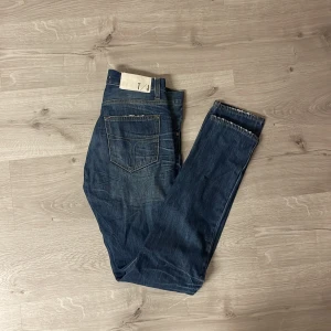 Blå jeans med raka ben - Snygga blå jeans  och raka ben. Jeansen har en mörk tvätt med lätt slitning och kontrastsömmar. Materialet är robust denim som ger en cool och avslappnad look. Perfekta för dig som gillar en tidlös stil.