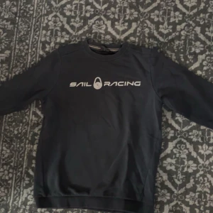 Sail Racing kofta - En Sail Racing kofta med text och logga fram och logga på baksidan. Perfekt under hösten.