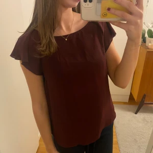 Vinröd blus med volangärmar - Säljer en vinröd blus med korta volangärmar och rund halsringning. Blusen har en flowy och lätt passform, materialet känns tunt och luftigt.