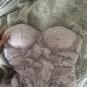 Ljuslila kort klänning från Eilly Bazar - Superfin ljuslila kort klänning från Eilly Bazar med blommigt mönster och paljettdetaljer.  (aldrig använd)