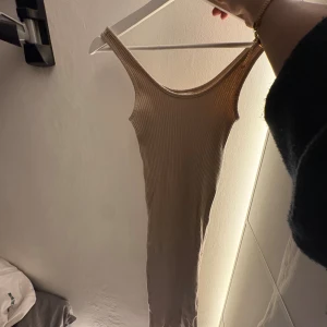 Beige ribbad långklänning H&M XS - Säljer en beige ribbad långklänning från H&M i storlek XS. Klänningen är ärmlös med rund halsringning och har en tight passform som framhäver figuren. Perfekt för dig som gillar en enkel men snygg look.