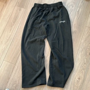 Svarta mjukisbyxor från YoungLA L - Svarta mjukisbyxor från YoungLA i storlek L. Byxorna har elastisk midja med snörning, en bakficka och broderad logga framtill. Tillverkade i mjukt material som är perfekt för chill eller träning.