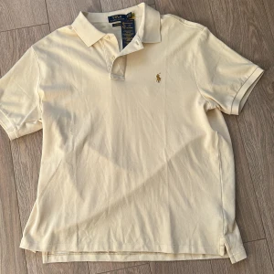 Beige pikétröja Polo Ralph Lauren XL - Snygg beige pikétröja från Polo Ralph Lauren i bomull. Klassisk krage, två knappar och broderad logga på bröstet. Custom slim fit för en modern look. Aldrig använd.