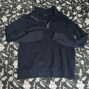 Mörkblå half zip sweatshirt - Mörkblå sweatshirt med half zip-dragkedja och hög krage. Tröjan har långärmad passform och är gjord i mjuk bomull, perfekt för lager-på-lager. Enkel och stilren design som funkar till det mesta. Storlek 165