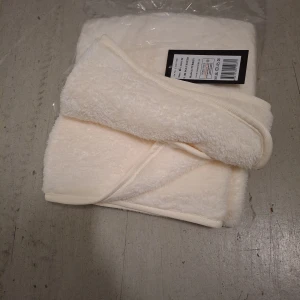 Cremfärg fluffig filt i polyester - Mysig och fluffig remfärg filt  i mjuk polyester. Enkel design med rundad form och bred kant, perfekt för kalla dagar när du vill hålla värmen och ändå se stilren ut.