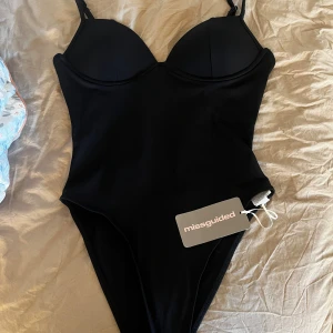 Svart body från Missguided XS - Snygg svart body från Missguided i storlek XS. Modellen har vadderade kupor, justerbara axelband och en stilren, enkel design. 