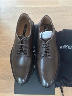 Nya  skor från Tiger of Sweden, nypris 2499 kr - Helt nya skor från Tiger of Sweden, modell Sagathon. Grym modell med fina detaljer på sulan. Perfekta för dig som gillar en clean och dressad look. Nypris 2499 kr Storlek 41  Kartong o skopåsar medföljer