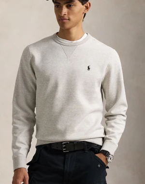 Grå sweatshirt från Polo Ralph Lauren - Klassisk grå sweatshirt från Polo Ralph Lauren med broderad marinblå logga på bröstet. Tröjan har rund halsringning, ribbade muddar och är tillverkad i mjuk bomullsmix. Perfekt för en clean och avslappnad stil.