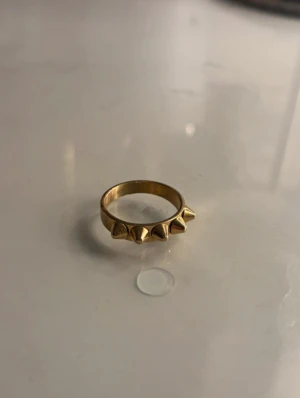 Edblad ring guld - Säljer en cool guldfärgad ring från Edblad med fem konformade nitar längs ovansidan. Ringen är i metall och I gulf färg och säljer den eftersom att jag köpt en likadan i silver 💕 ringen är inte för stor eller för liten utan helt perfekt! (PRIS KAN DISKUTERAS!)