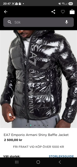 Svart glansig pufferjacka EA7 Armani - Svart glansig pufferjacka från EA7 Emporio Armani med stor logga längs dragkedjan. Jackan har huva, lång ärm och quiltad design. Materialet är syntet och jackan stängs med dragkedja. Perfekt för dig som vill sticka ut med en clean och modern look. Använd en gång, i nyskick. Köpt på JD sports, storlek XXL, men känns som en tight XL. Snygg jacka, men tyvärr för tight runt bröstet för mig (bodybuilder 182cm 100kg)
