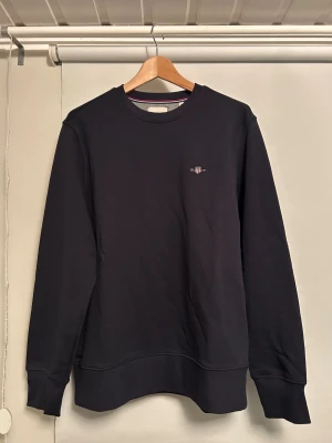 Mörkblå tröja från Gant M  - Snygg blå tröja från gant. Den är långärmad och har en bra passform med en bra kvalite. Den är i väldigt bra skick för har inte använt den någon gång innan. 