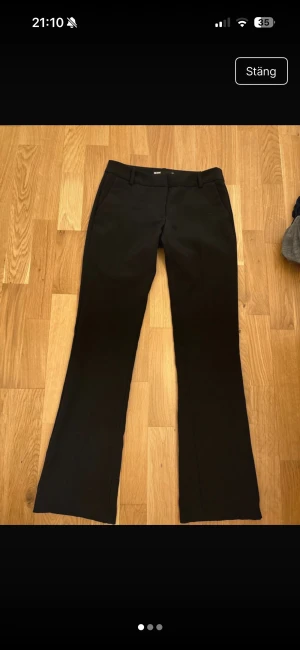 Svarta low waist kostymbyxor från Bik Bok - Snygga svarta kostymbyxor från Bik Bok med klassisk rak passform och bootcut. Byxorna har bälteshällor, sidfickor fram och dekorativa fickor bak. Perfekta för en clean och stilren look. Materialet är mjukt och har lite stretch för extra komfort. Endast använda en gång! Nypris: 500.