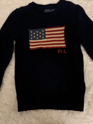 Mörkblå stickad tröja Ralph Lauren - Snygg mörkblå stickad tröja från Ralph Lauren med amerikansk flagga i rött, vitt och blått på bröstet. Storlek XXS. Nypris: 4895kr Använd en gång. Skickas nytvättad. 