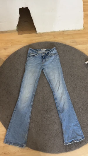 Bootcut ljusblå jeans - Snygga ljusblå jeans med klassisk bootcut-passform och fem fickor. Jeansen har en låg midja och är tillverkade i mjukt denimtyg. Perfekt för dig som gillar retrovibbar och vill ha ett par jeans med lite utsvängda ben.