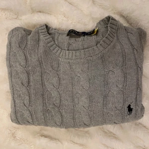 Grå kabelstickad tröja Polo Ralph Lauren - Snygg grå kabelstickad tröja från Polo Ralph Lauren med rund hals | Nypris runt 2500kr