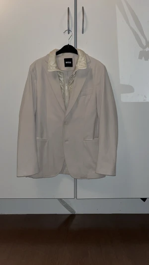 Mycket stilig kavaj jacka från boss i nyskick - Beige kavaj jacka från boss med avtagbar innerjacka i fint skick. Endast använd 2 gånger och är storlek 48, alltså S/M. Nypris ligger på 4000+.