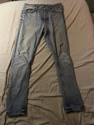 Ljusblå jeans från Nudie Jeans Co W30 L32 - Säljer ett par Ljusblåa Nudie Jeans i storlek W30 L32. Jeansen är väll använda och har stora defekter (skador). Kolla NOGA på alla bilder för se hur skadorna ser ut. Hör av dig vid frågor