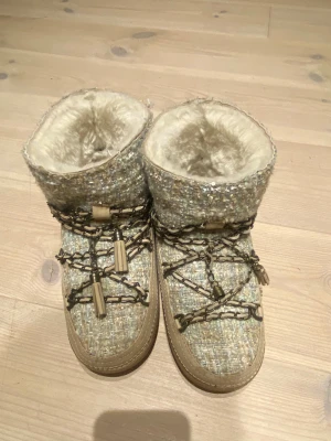 Inuikii - Moon boots från Inuikii i beige med stickad textil, ”tofsen” på ena skon fattas (se sista bilden) men inget man tänker på så mycket, annars bra skick🩷