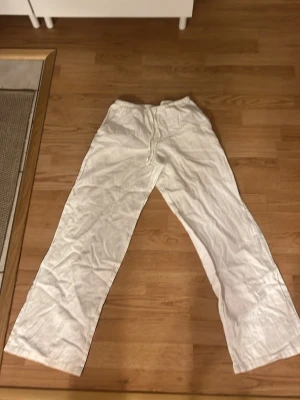 Vita linnebyxor från Gina Tricot - Snygga och luftiga vita linnebyxor från Gina Tricot med resår och snörning i midjan. Perfekta för varma dagar, raka ben och avslappnad passform. Stilrena och enkla att matcha med det mesta.