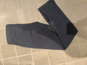 Mörkblå chinos från Lindbergh white  - Snygga mörkblå chinos från lindbergh white med raka ben och klassisk passform. Byxorna har bälteshällor, sidofickor och en bakficka med knapp. Perfekta för en clean och stilren look. Tillverkade i mjuk bomull för skön känsla hela dagen.