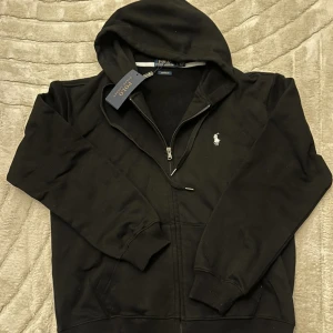 Polo zip - Snygg svart zip-hoodie från Polo Ralph Lauren. Original. Mjuk och bekväm kvalitet, perfekt till vardags. Märkt storlek L men sitter mer som S/M. Bra skick utan hål eller fläckar. Dragkedja fungerar som den ska.