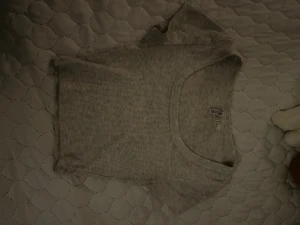 Grå ribbad croppad topp  - En ljusgrå croppad topp från H&M med ribbad struktur. Toppen har korta ärmar och rund halsringning, perfekt för en chill och stilren look. Enkel att matcha med jeans eller kjol för en avslappnad vibe.