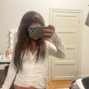 Vit omlottopp med knyt i sidan - Säljer en vit omlottopp med långa ärmar och snygg v-ringning. Toppen har knyt i sidan som ger en schysst passform och lite extra detalj. Perfekt att styla med jeans eller kjol för en clean look. Storlek M men sitter som S/XS