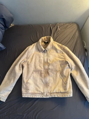 Beige jeansjacka / utility jacka - Säljer en beige jeansjacka från H&M med klassisk krage och dragkedja framtill. Jackan har två stora fickor på framsidan och raka ärmar. Perfekt för dig som gillar en enkel och stilren look.