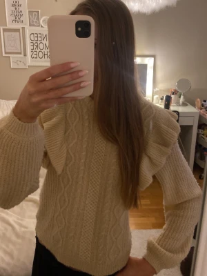 Beige stickad tröja med volang från JDY - Superfin beige stickad tröja från JDY med snygga volangdetaljer på axlarna och klassiskt flätmönster framtill. Tröjan har rund hals och långa ärmar. Jättefint skick💞