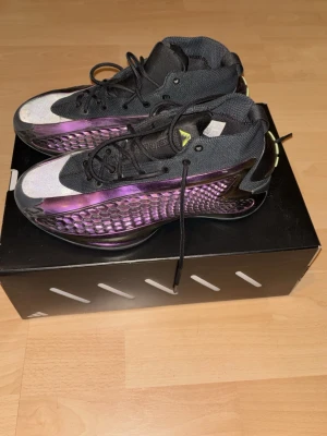Adidas AE 1 sneakers svart/lila - Säljer ett par Adidas AE 1 sneakers i svart och lila med coolt hexagonmönster på sidan. Skorna har snörning, mesh- och syntetmaterial samt en chunky sula. Perfekta för dig som vill sticka ut med futuristisk vibe och sportig look. Säljer med sko box om man undrar. 