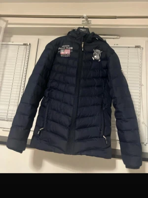 Vinson Polo Club Navy Blue Puffer Jacket - Stylish navy blue puffer jacket from Vinson Polo Club. Classic sporty design with embroidered logos on the front and a large USA flag print on the back. Warm and comfortable, perfect for autumn and winter. Zipper closure, hood, and side pockets. ✔ Size: S ✔ Color: Navy Blue ✔ Condition: Very good / gently used ✔ Brand: Vinson Polo Club No stains or damage. Clean and well taken care of. Feel free to message me if you have any questions! 